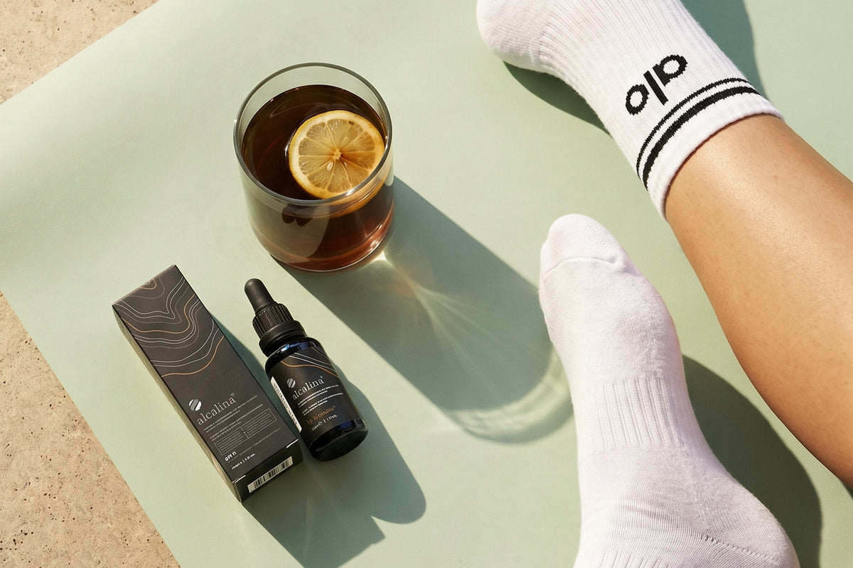 An alcalina dropper bottle and a glass beside a yoga mat
