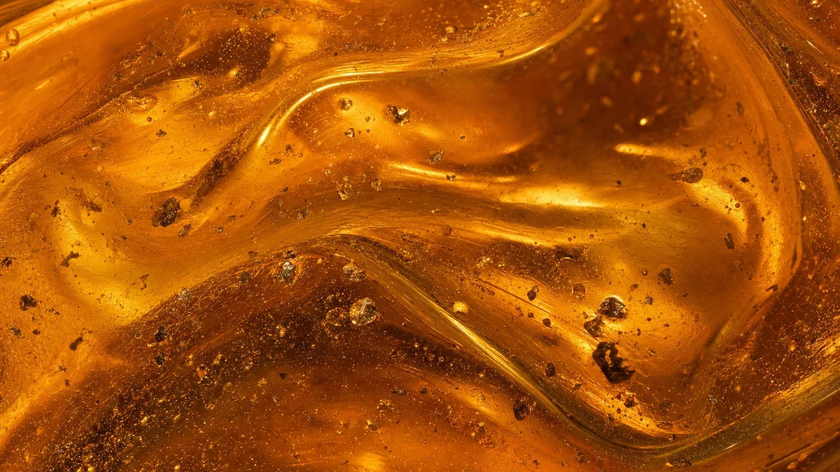 Thick golden-amber mineral concentrate lit from behind, swirling slowly