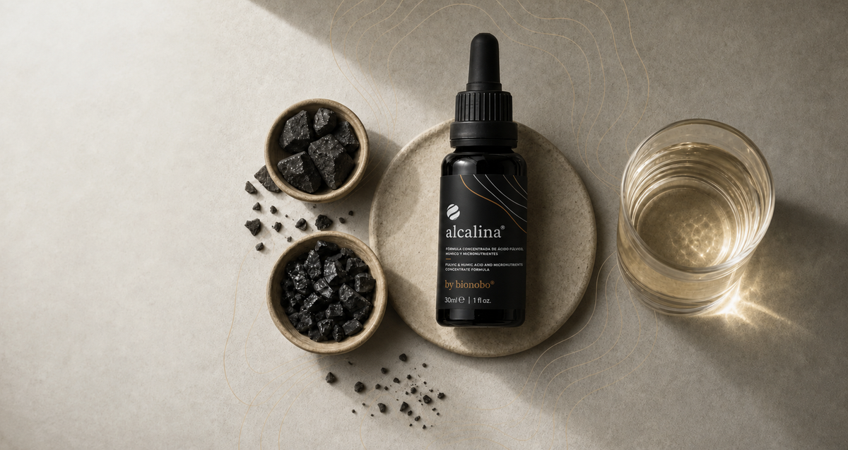 Alcalina fulvic-acid dropper bottle with mineral stones and a glass of clear golden water.